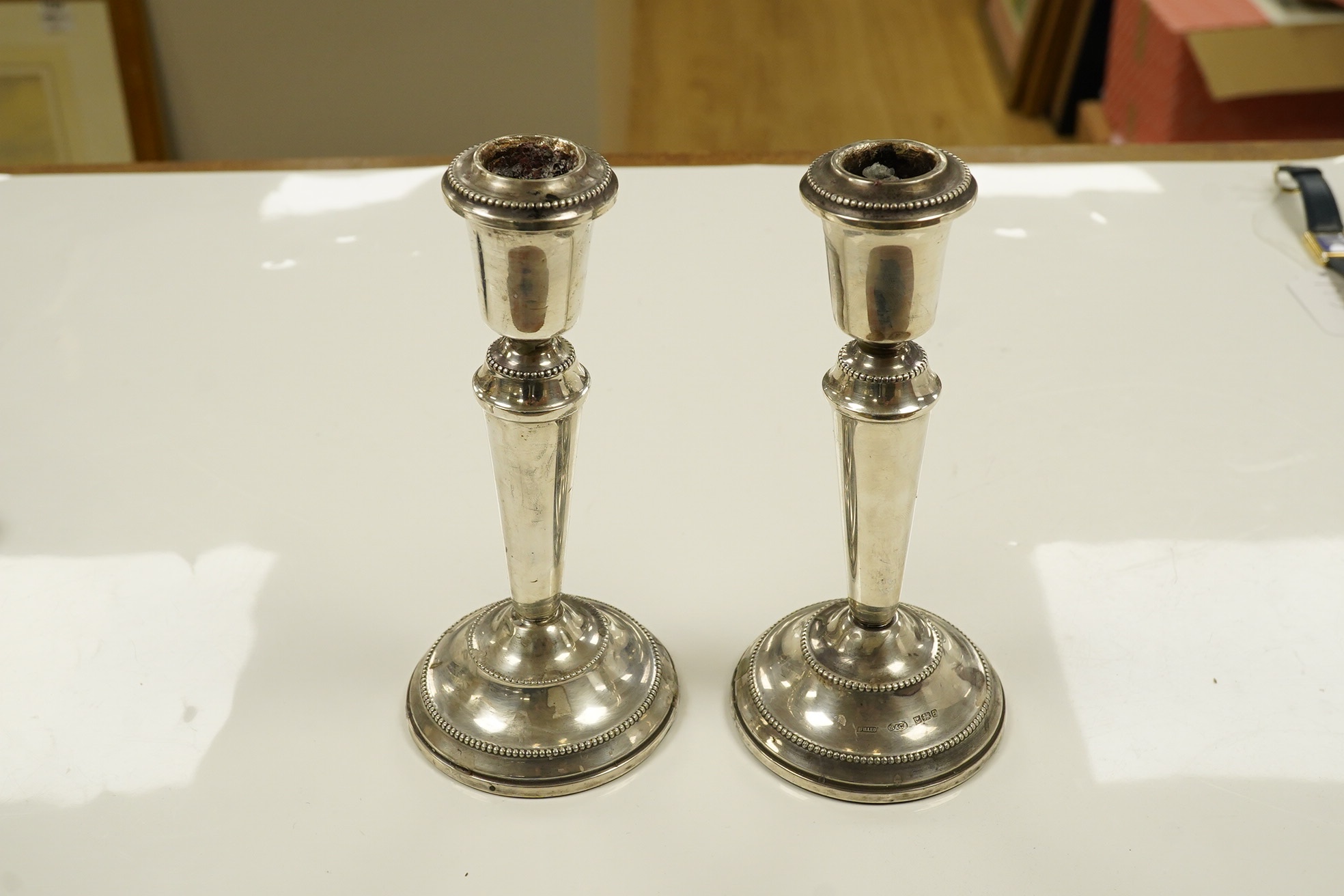 A pair of modern loaded silver candlesticks, 18cm high, an embossed silver mounted photograph frame, 20cm and a plain rectangular photograph frame, 16cm. Condition - fair to good